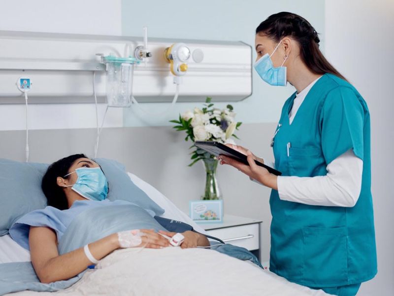 nurse talks with patient in hospital bed
